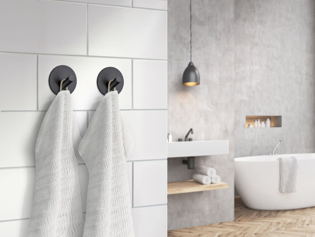 två mattsvarta självhäftande handdukskrokar i vitt och grått badrum